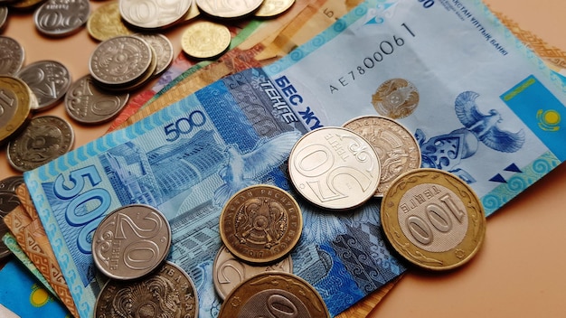 Tenge. Money. Kazakh coins and bills are on the beige table close-up.