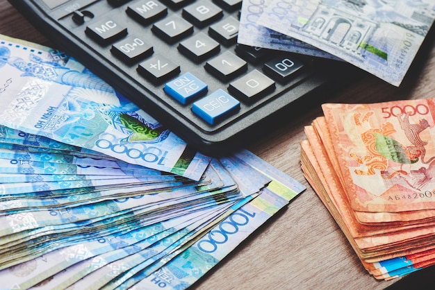 Tenge. Paper Kazakh money and calculator on the table close-up.