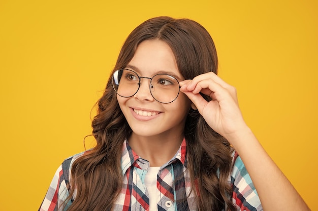 Tennager child girl wear eyeglasses looking at camera with confidence over yellow background copy space Kid get eyesight