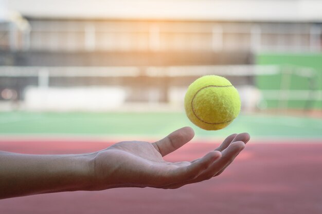 Photo tennis ball is floating on the hand and blur court background