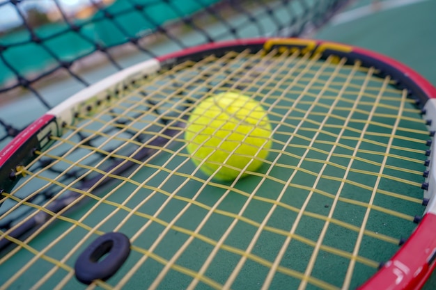 tennis ball and racket on hard court