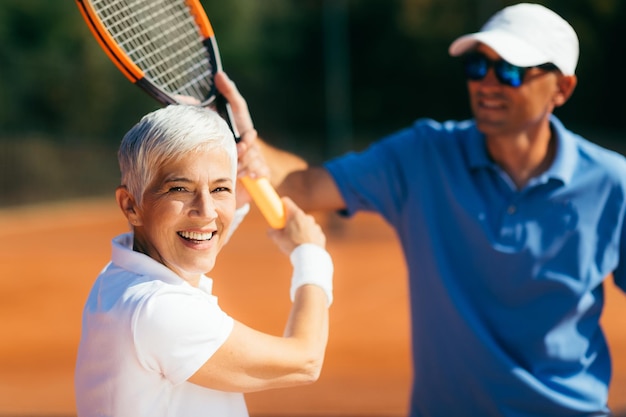 Tennis Instructor Teaching Elderly Woman How to Play Tennis