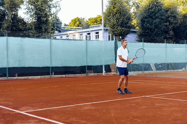 Tennis player standing with racket on outdoor tennis court