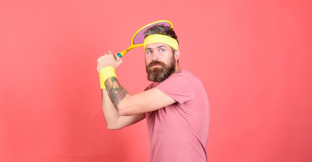 Tennis player vintage fashion tennis sport and entertainment\
athlete hipster hold tennis racket in hand red background man\
bearded hipster wear sport outfit having fun tennis active\
leisure
