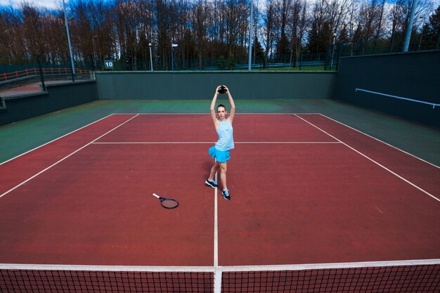 Giocatore di tennis in abito bianco e tacchi con racchetta da tennis sul campo
