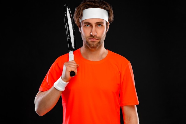 Photo tennis player with racket in orange tshirt man athlete playing isolated on black background