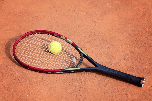 Tennis racket and balls on the clay court