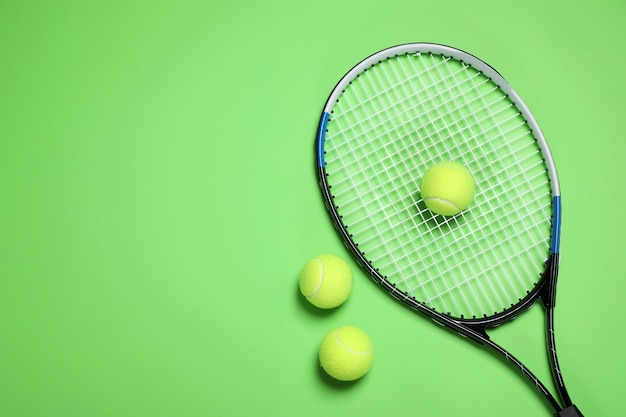 Tennis racket and balls on green background flat lay Space for text