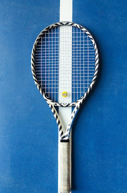 Tennis racket lies on a blue tennis surface Top view Vertical photo