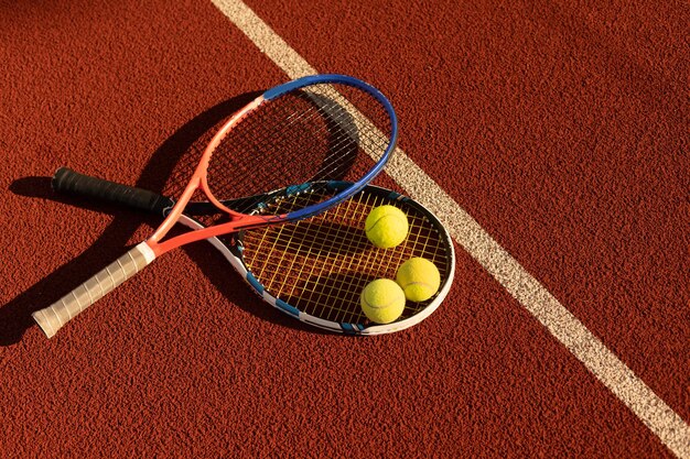 A tennis racket and new tennis ball on a freshly painted tennis court.