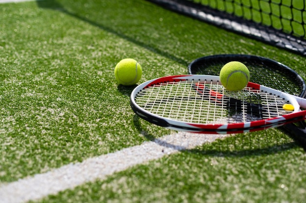 Una racchetta da tennis e una nuova pallina da tennis su un campo da tennis dipinto di fresco