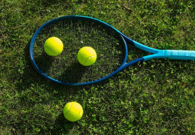 Tennis racket with balls on the grass