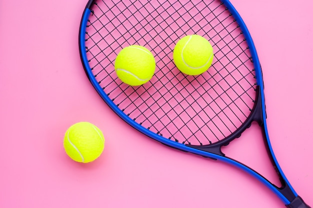 Tennis racket with balls on pink surface