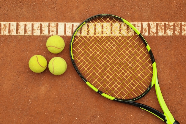 Tennis racquet with tennis balls on clay court