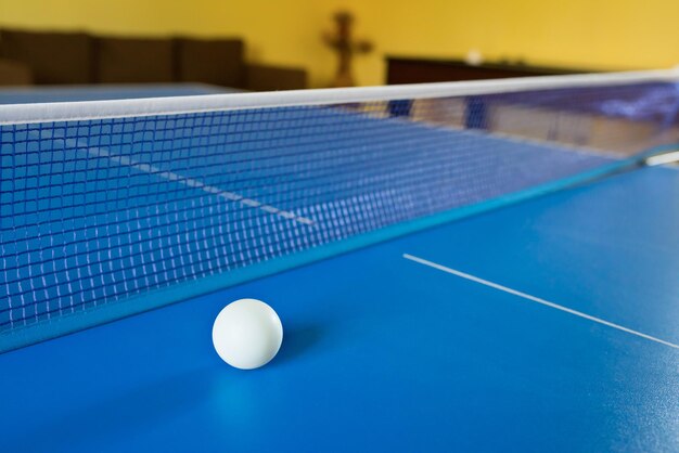 A tennis white ball for ping-pong on a blue table a ping-pong game sport games