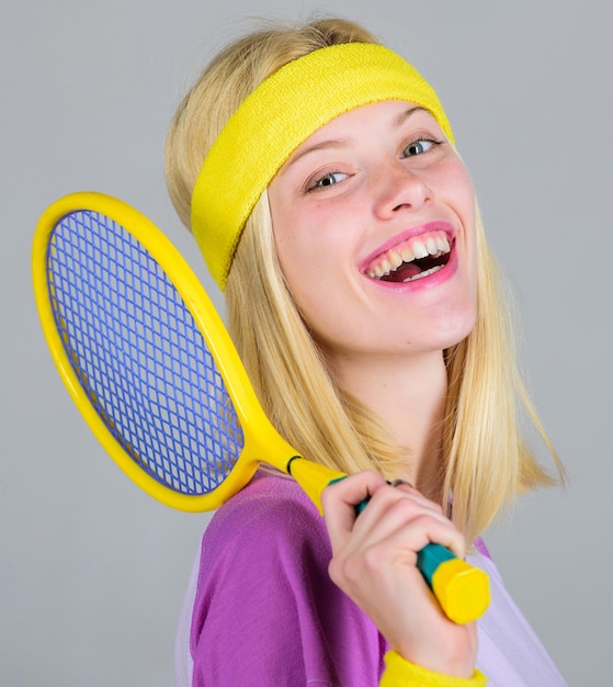 Tennisclubconcept. Meisje schattig blond tennissen. Sporten voor het behoud van de gezondheid. Atleet tennisracket in de hand houden op grijze achtergrond. Actieve vrije tijd en hobby. Tennissport en amusement.