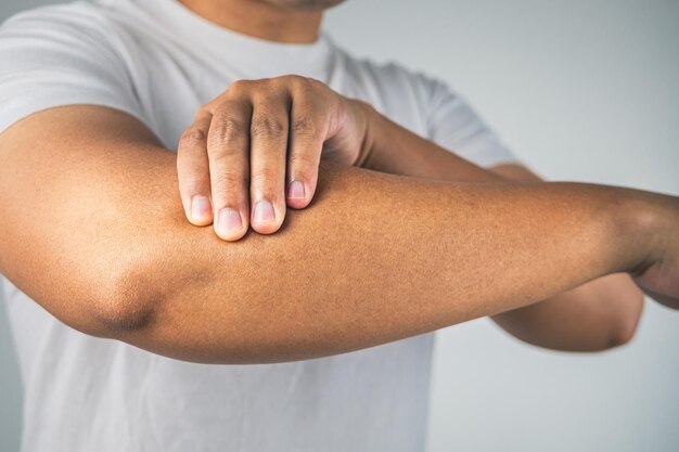 Tenniselleboogconcept De man gebruikt vingers om zijn arm te masseren Kennis van de gezondheidszorg Medium close-up shot