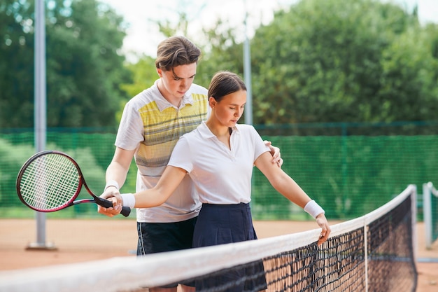 Tennisleraar leert meisje het racket vast te houden