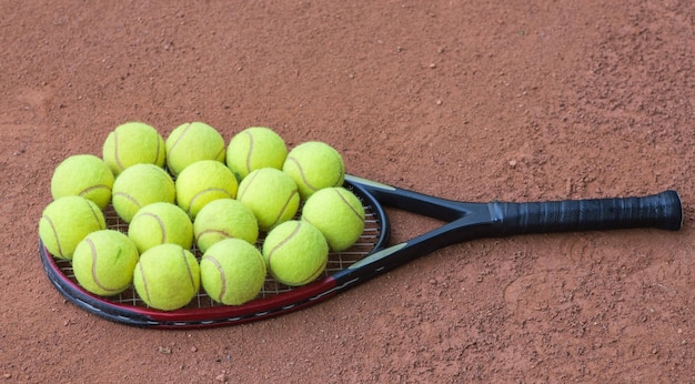 Tennisracket en ballen op de gravelbaan