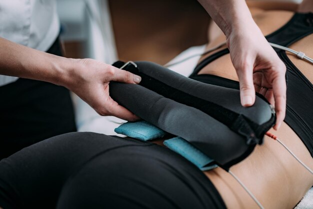 Photo tens transcutaneous electrical nerve stimulation in physical therapy therapist positioning electrodes onto patients lower back