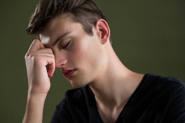 Tense androgynous man with hand on forehead