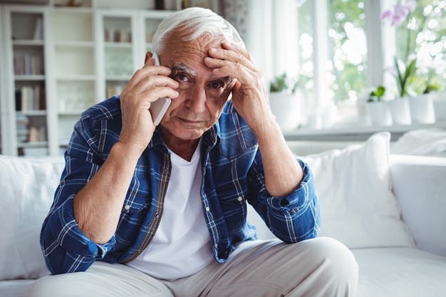 Tense senior man talking on mobile phone