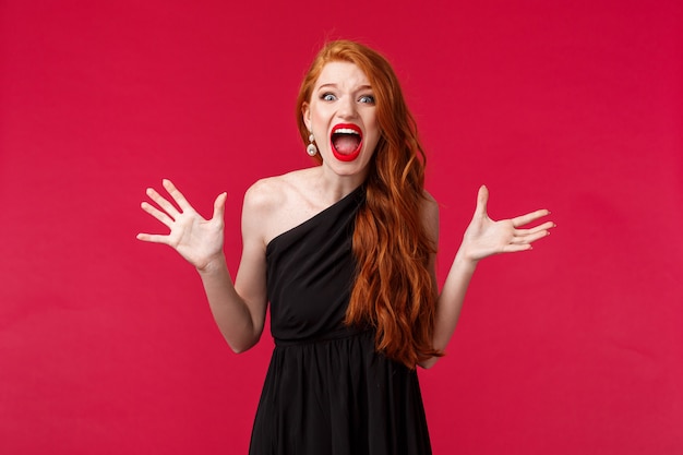 Tensed and aggressive, pissed-off young redhead woman found out best friend slept with her boyfriend, arguing having argument and confrontation on party, screaming at person, red wall