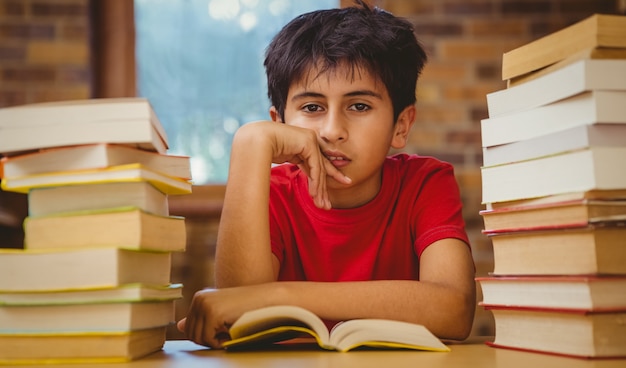 Tensed boy sitting with stack of books