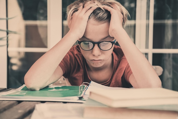 Photo tensed boy studying on table at home