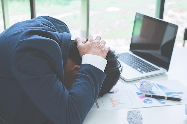 Tensed businessman leaning at desk in office