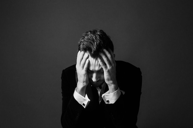 Photo tensed businessman sitting against gray background