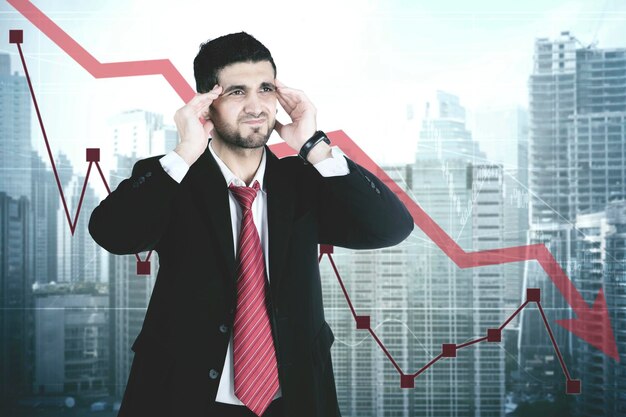 Photo tensed businessman standing against graph and buildings in city