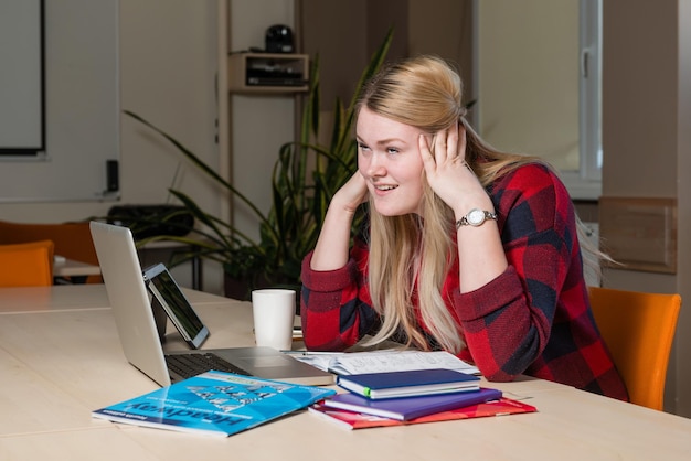 Фото Напряженная бизнесменка использует технологии, сидя за столом в офисе.