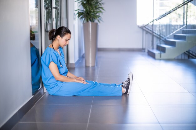 Medico femminile teso che si siede in corridoio