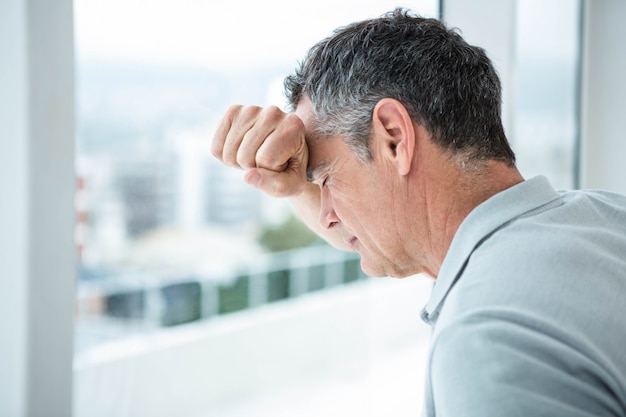 Tensed man leaning on glass window at home