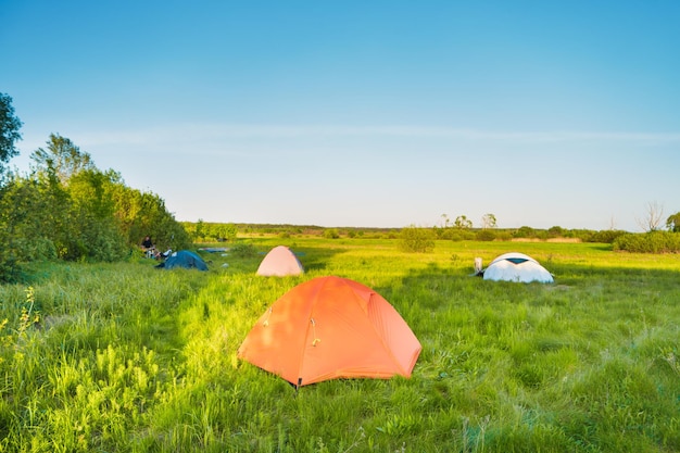 숲의 푸른 잔디밭에서 일몰에 텐트 캠프 캠핑