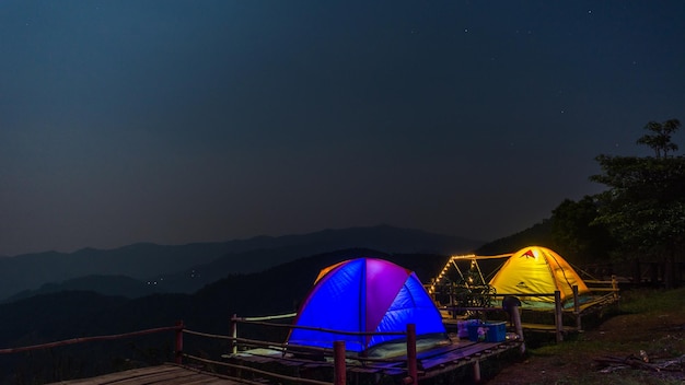 写真 夜空を背景に山の上にテントを張る