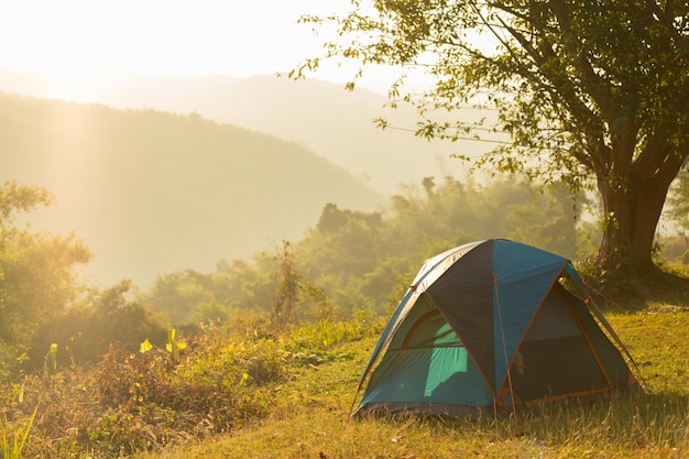 Tent op het veld tegen de bergen bij zonsondergang
