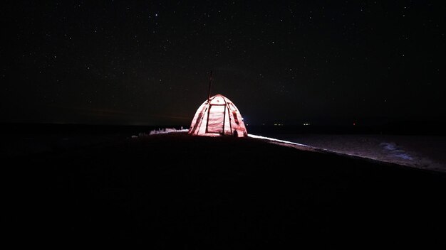 A tent with a stove stands under the starry sky