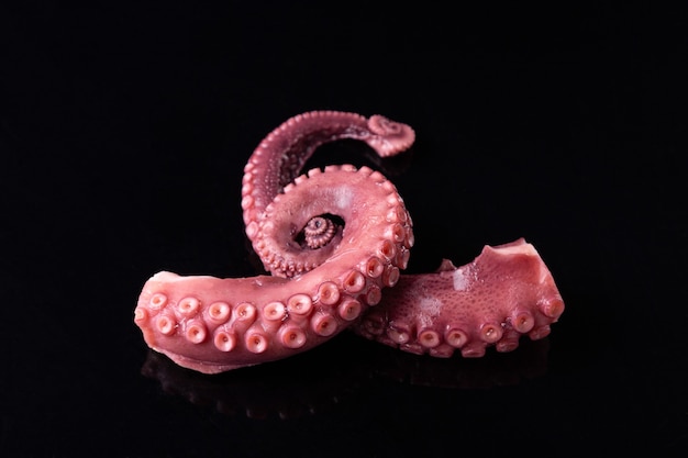 Tentacoli di polpo stufato isolato su sfondo scuro.