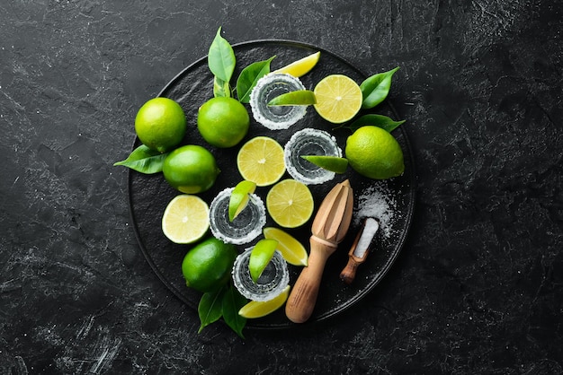 Tequila salt and lime Alcohol On a black stone background Top view Free space for your text