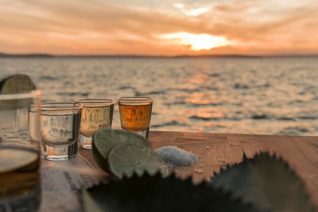 夕暮れの海を背景にテーブルに置かれたショットグラスの中のテキラ