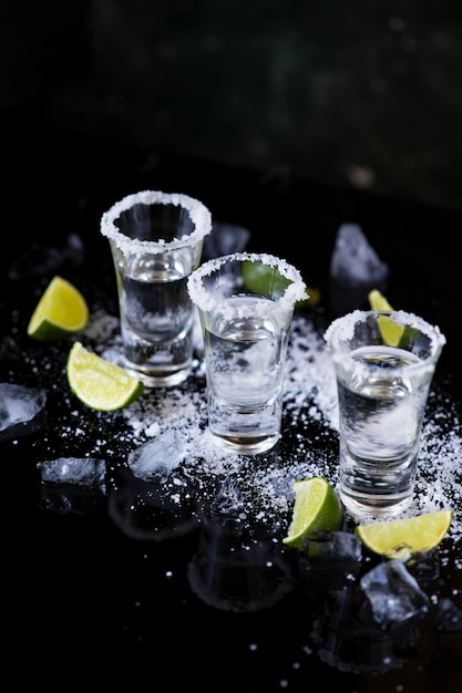 Photo tequila shot with lime and salt on black background