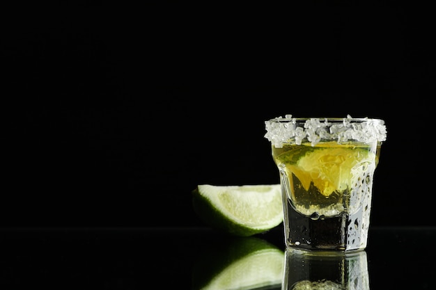 Tequila shot with lime and sea salt on black