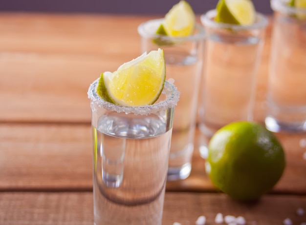 Photo tequila shot with lime and sea salt onwooden table