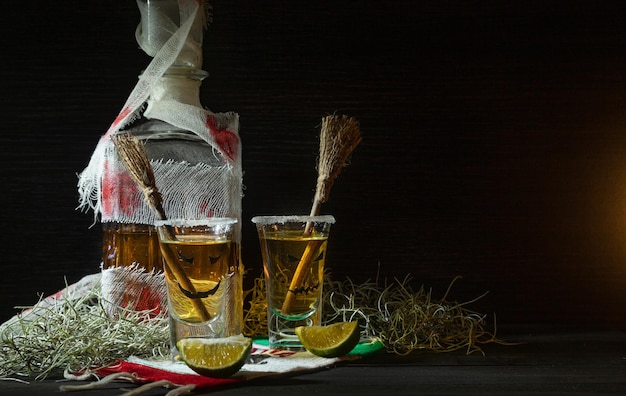 Tequila-shots met halloween-decoratie verbonden flesglazen met enge gezichten en heksenbezems