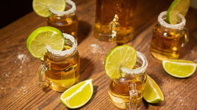 Tequila shots served in jars with salt and lime on wooden table