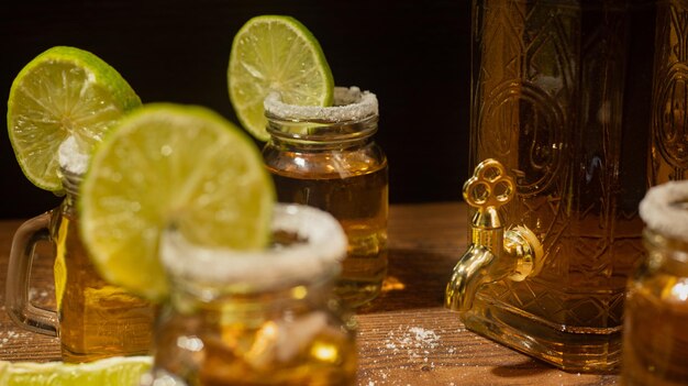 Tequila shots served in jars with salt and lime on wooden table