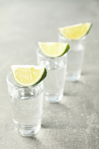 Tequila shots with lime slices on grey