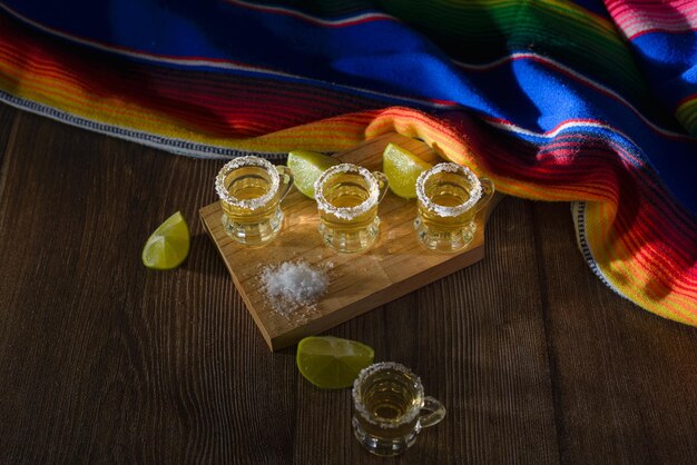 Tequila shots with salt and lime on a bar table Shots of tequila and typical mexican elements